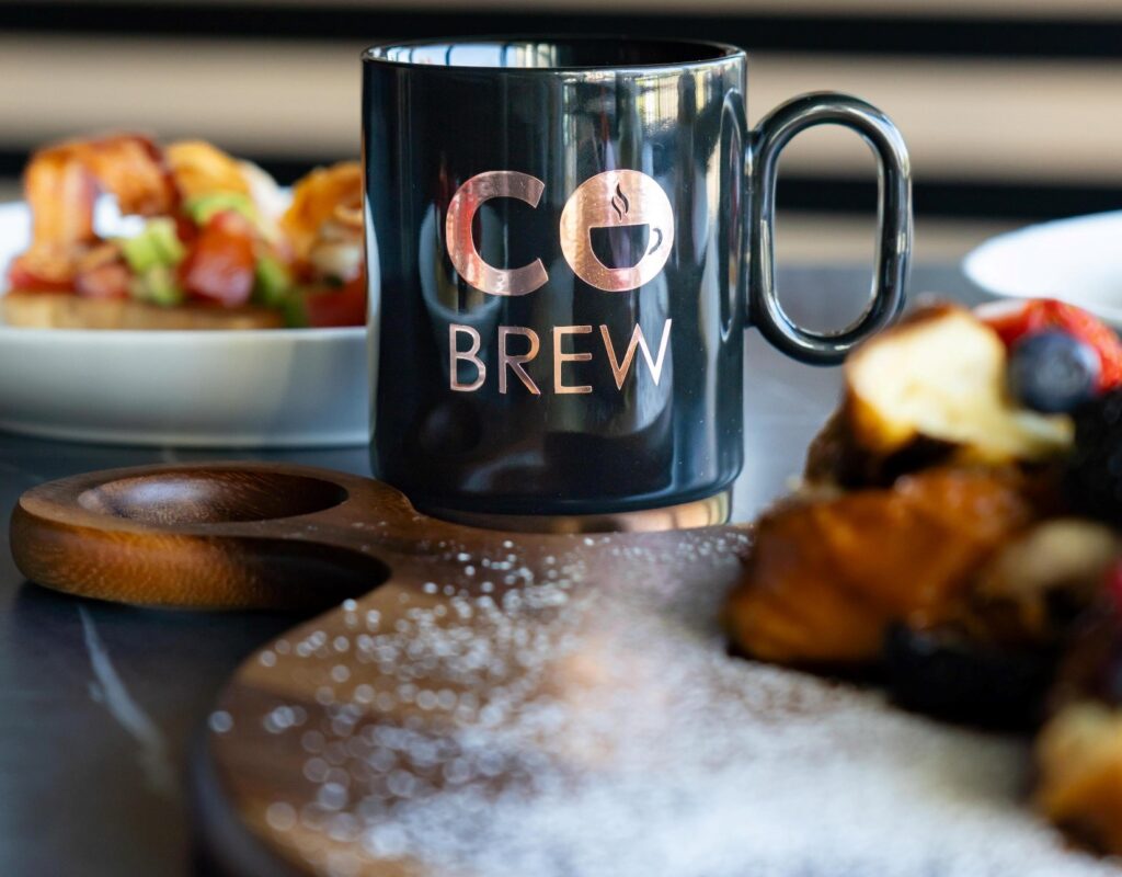 Black CoBrewmug with gold CoBrew logo surrounded by food